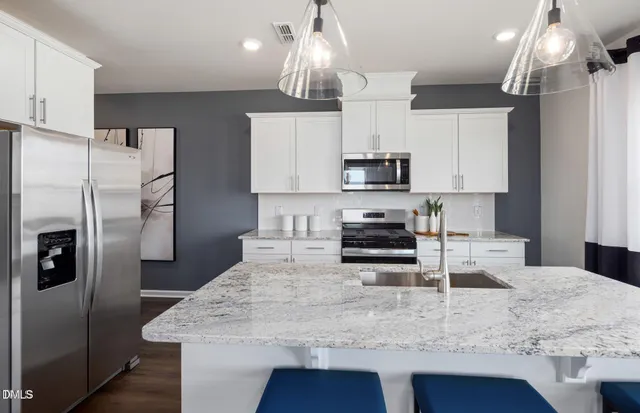 a kitchen with kitchen island granite countertop a refrigerator a sink a stove a oven a counter space and cabinets