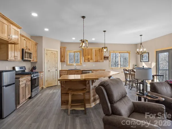 a kitchen with stainless steel appliances granite countertop a stove top oven a refrigerator a sink dishwasher a dining table and chairs with wooden floor