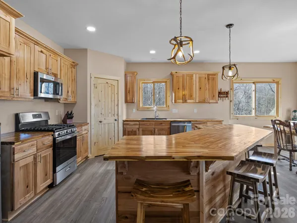 a kitchen with granite countertop a stove a sink a oven a dining table and chairs with wooden floor