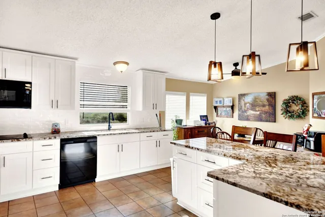 a large kitchen with kitchen island granite countertop a sink a stove and cabinets