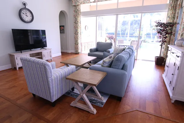 a living room with furniture a flat screen tv and a floor to ceiling window