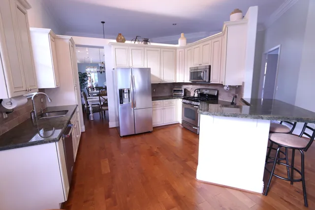 a kitchen with stainless steel appliances a refrigerator a stove a sink dishwasher and a microwave with wooden floor