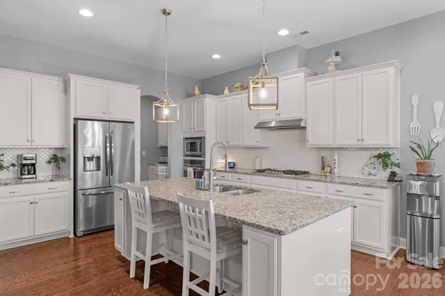 a kitchen with stainless steel appliances granite countertop a table chairs refrigerator and cabinets