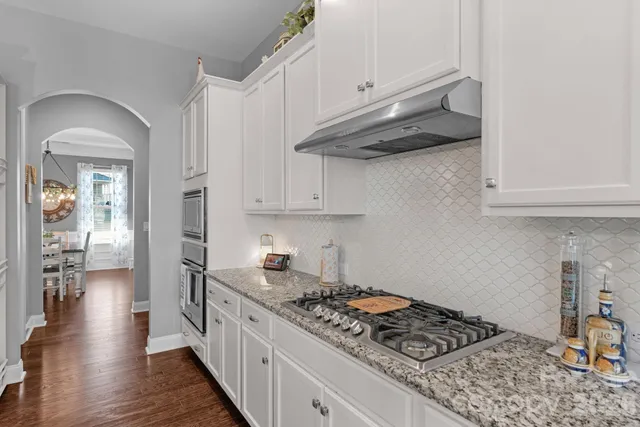 a kitchen with stainless steel appliances granite countertop a stove and a wooden floors