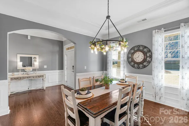 a dining room with wooden floor a chandelier a wooden table and chairs
