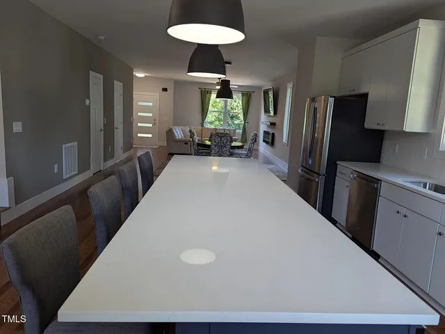 a kitchen with stainless steel appliances a dining table chairs and stove top oven