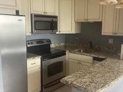 a kitchen with stainless steel appliances granite countertop a stove a refrigerator and a white cabinets
