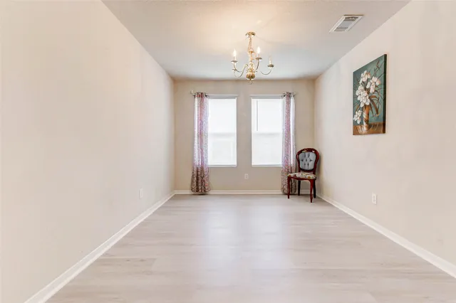 an empty room with windows and chandelier fan