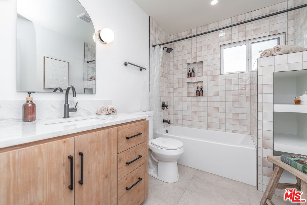 Undisclosed Address Los Angeles, CA 90008 - Photo 18 of 28 a bathroom with a granite countertop sink a toilet a mirror a bathtub and shower