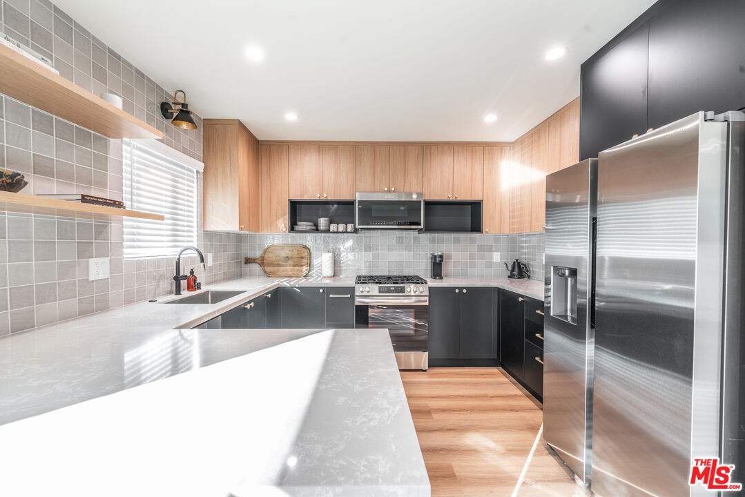 Undisclosed Address Los Angeles, CA 90008 - Photo 7 of 28 a large kitchen with stainless steel appliances kitchen island granite countertop a large counter top a stove a sink dishwasher a refrigerator and cabinets with wooden floor