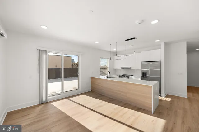 a large white kitchen with wooden floor and a sink