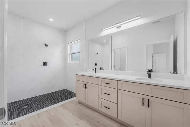 a spacious bathroom with a double vanity sink a mirror and a shower