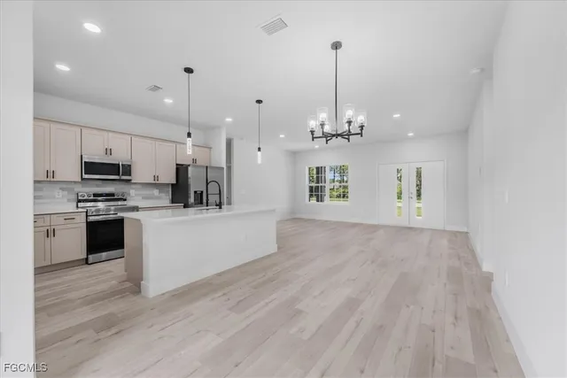 a large kitchen with kitchen island a stove a sink a refrigerator and a wooden floor