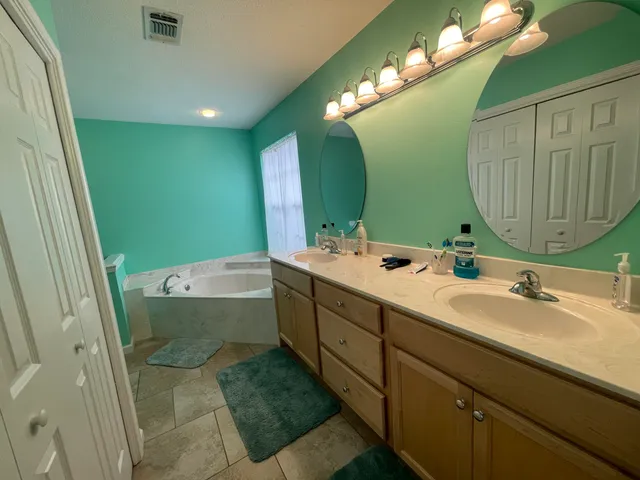 a bathroom with a double vanity sink mirror and bathtub