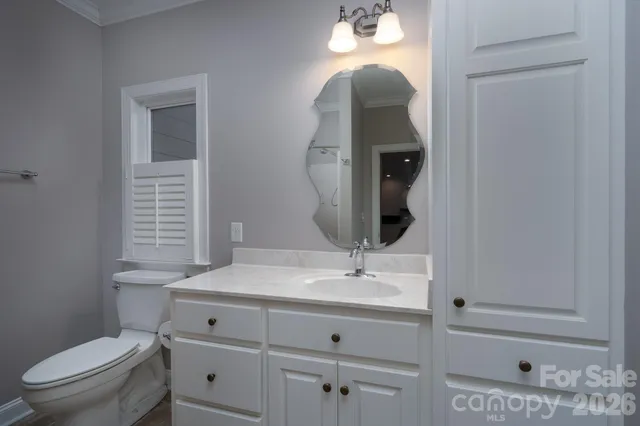 a bathroom with a granite countertop sink a toilet a mirror and shower