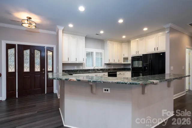 a kitchen with stainless steel appliances granite countertop a stove a sink a refrigerator and a oven with wooden floor