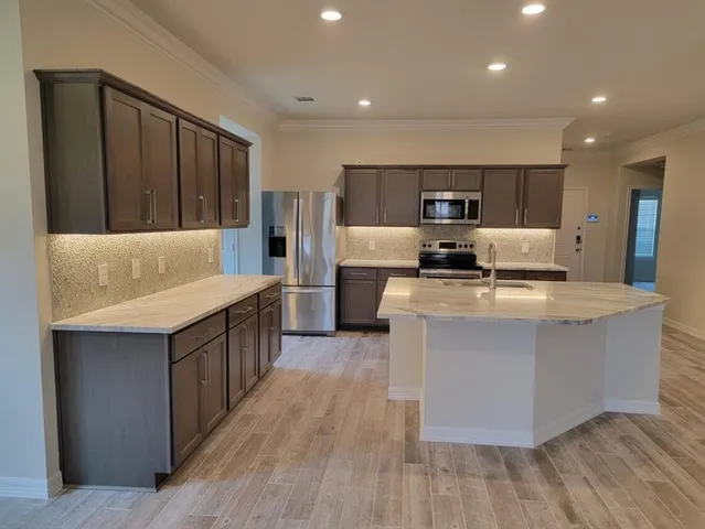 a living room with stainless steel appliances granite countertop a kitchen island a stove a sink and a refrigerator