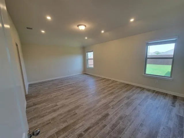 an empty room with wooden floor and windows