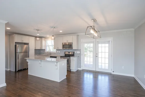 a kitchen with stainless steel appliances granite countertop a stove top oven a refrigerator cabinets and wooden floor