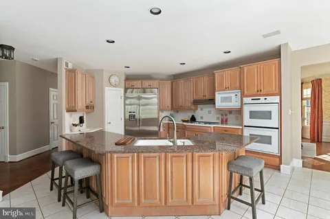 a kitchen with stainless steel appliances kitchen island granite countertop a table chairs and a refrigerator