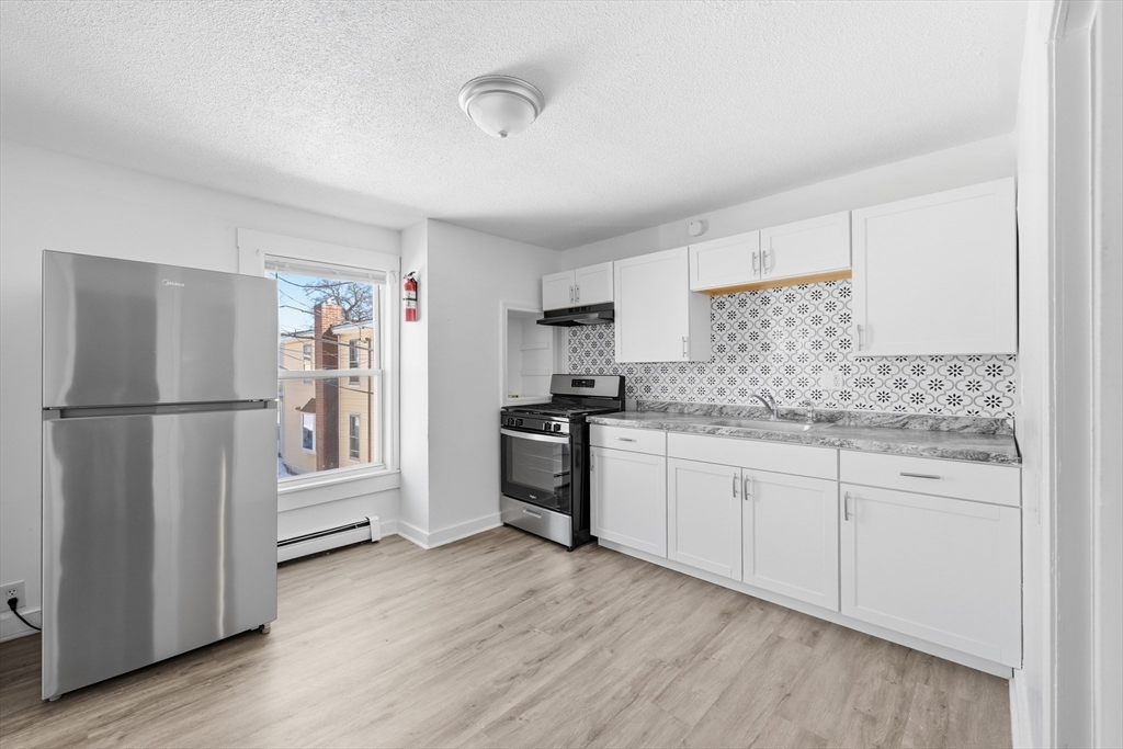 5 Floyd Street Lowell, MA 01852 - Photo 4 of 35 a kitchen with granite countertop white cabinets and stainless steel appliances
