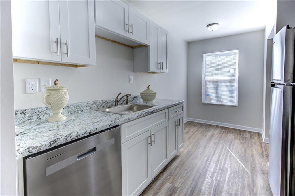2340 Beaver Ruin Road, Unit UN15 Norcross, GA 30071 - Photo 13 of 30 a kitchen with granite countertop white cabinets and a wooden floor