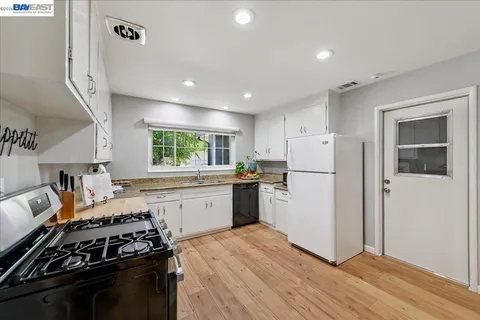 a kitchen with granite countertop a refrigerator stove top oven and sink