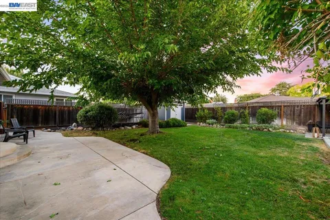 a view of a backyard with table and chairs under an umbrella