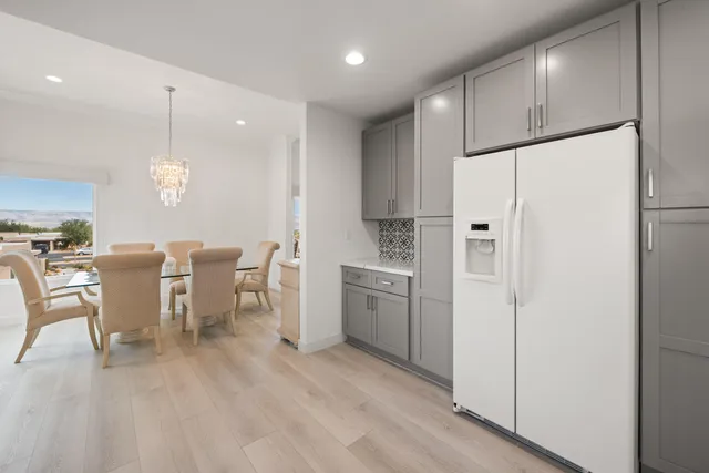 a kitchen with stainless steel appliances granite countertop a refrigerator a sink a stove a dining table and chairs