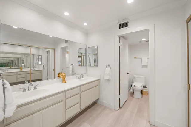 a spacious bathroom with a double vanity sink a mirror and a toilet
