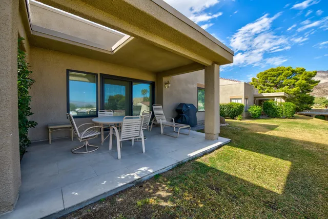 a view of a patio with table and chairs with plants and garden
