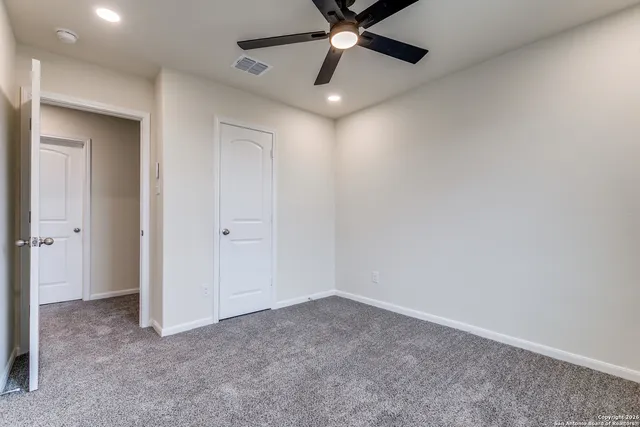 an empty room with a ceiling fan and window