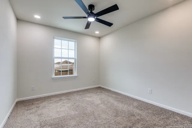 an empty room with a window and a fan