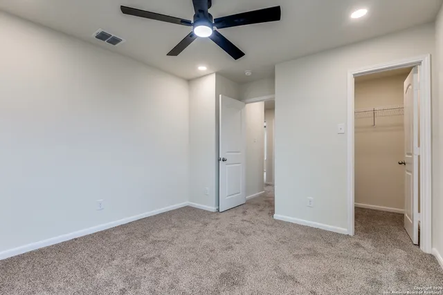 an empty room with closet and a ceiling fan