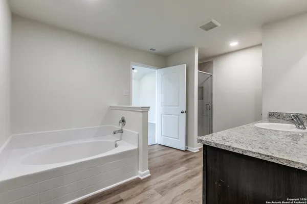 a bathroom with a granite countertop sink and a bathtub