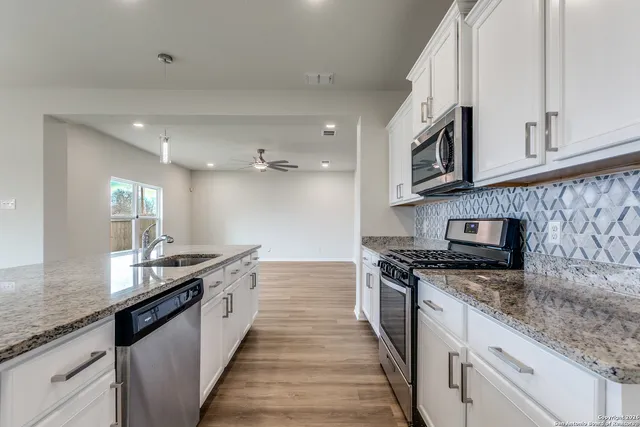 a kitchen with stainless steel appliances granite countertop a sink and dishwasher a stove top oven with wooden floor