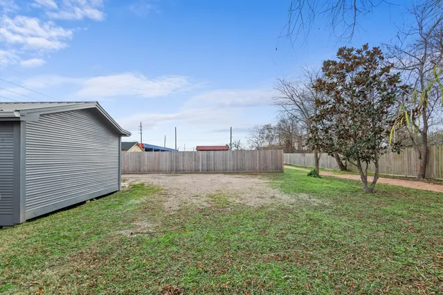 a view of a backyard with large trees and a barn