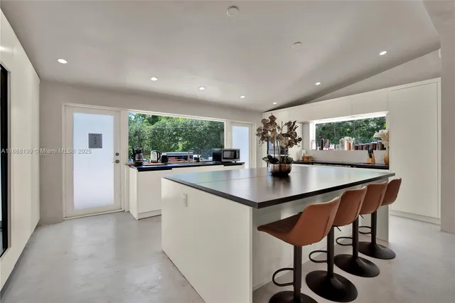 a kitchen with stainless steel appliances kitchen island a table and chairs in it