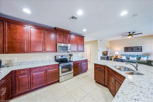 a kitchen with stainless steel appliances granite countertop wooden cabinets a sink dishwasher a stove and a refrigerator with wooden floor