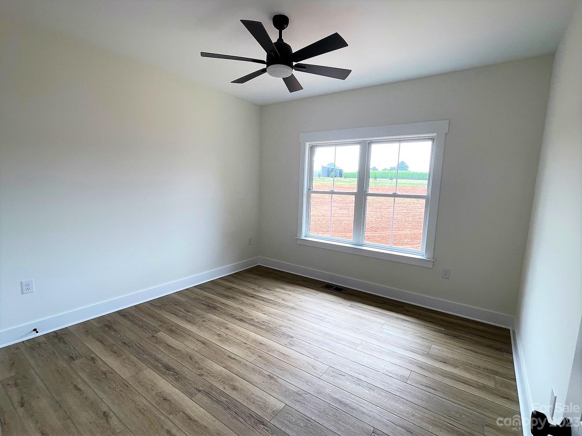215 Cal Kennedy Road Cleveland, NC 27013 - Photo 37 of 39 an empty room with wooden floor ceiling fan and windows