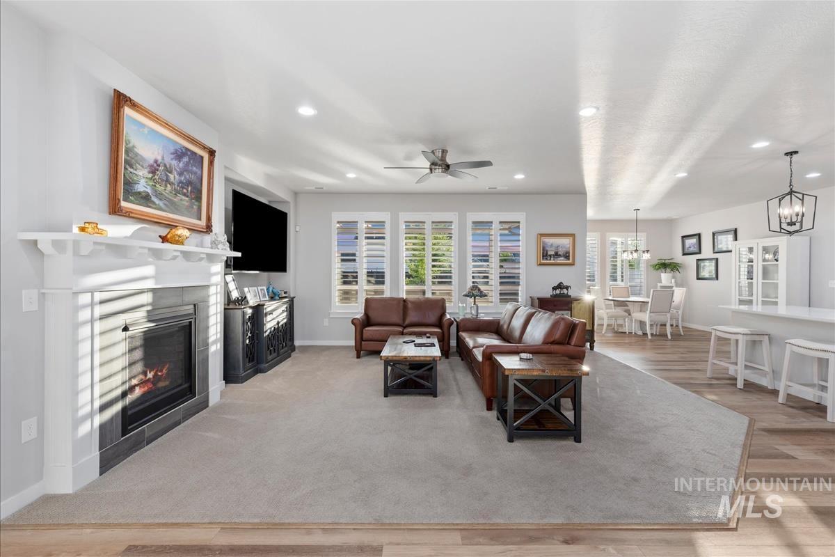15451 Lutsen Avenue Caldwell, ID 83607 - Photo 8 of 39 Spacious living area featuring a fireplace with a white mantel, light gray wall-to-wall carpeting, and a ceiling fan