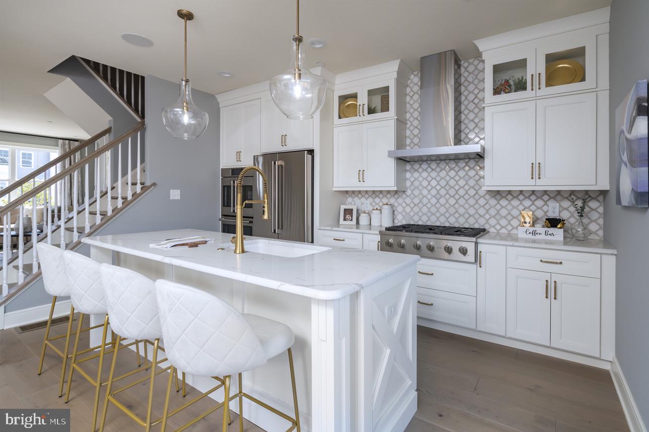 a kitchen with stainless steel appliances kitchen island a table chairs in it and white cabinets