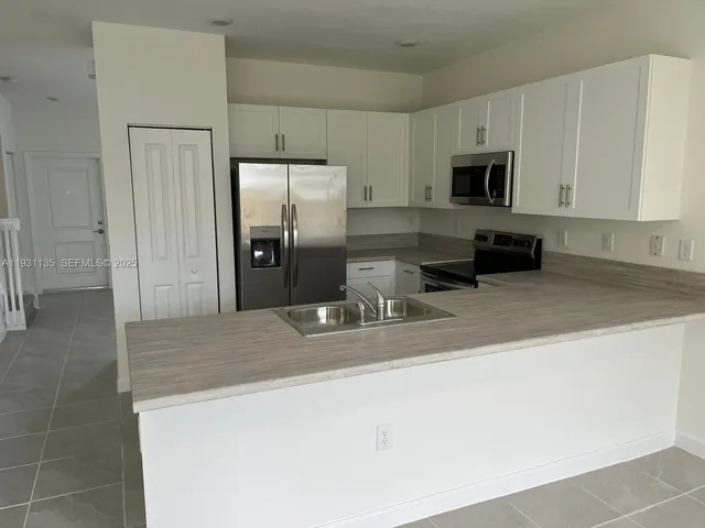 a kitchen with stainless steel appliances a sink a stove a microwave and refrigerator