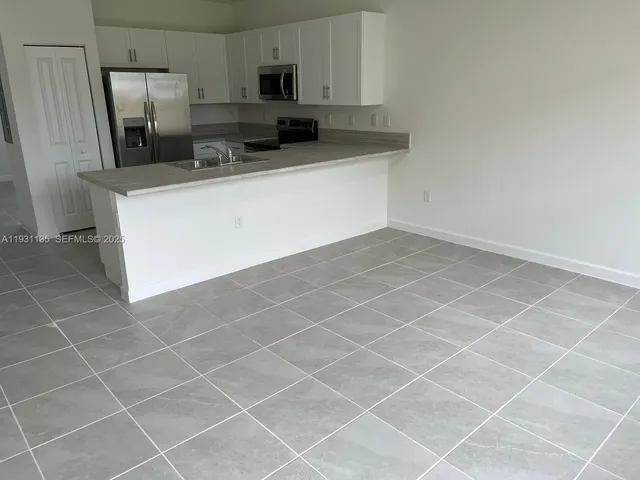 a kitchen with stainless steel appliances a sink a stove a microwave a refrigerator a sink and cabinets