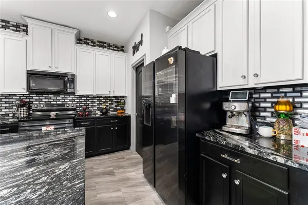 a kitchen with stainless steel appliances granite countertop a refrigerator a stove and a sink
