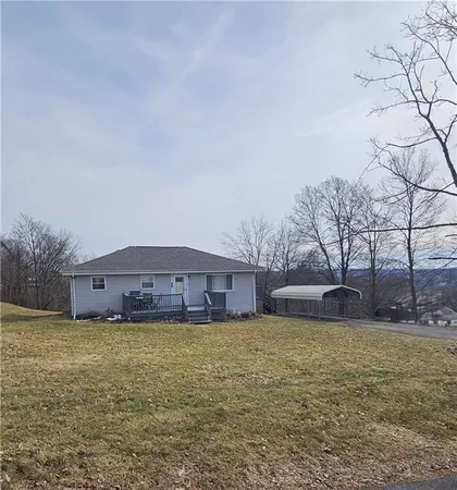 a view of a house with a yard and a large tree