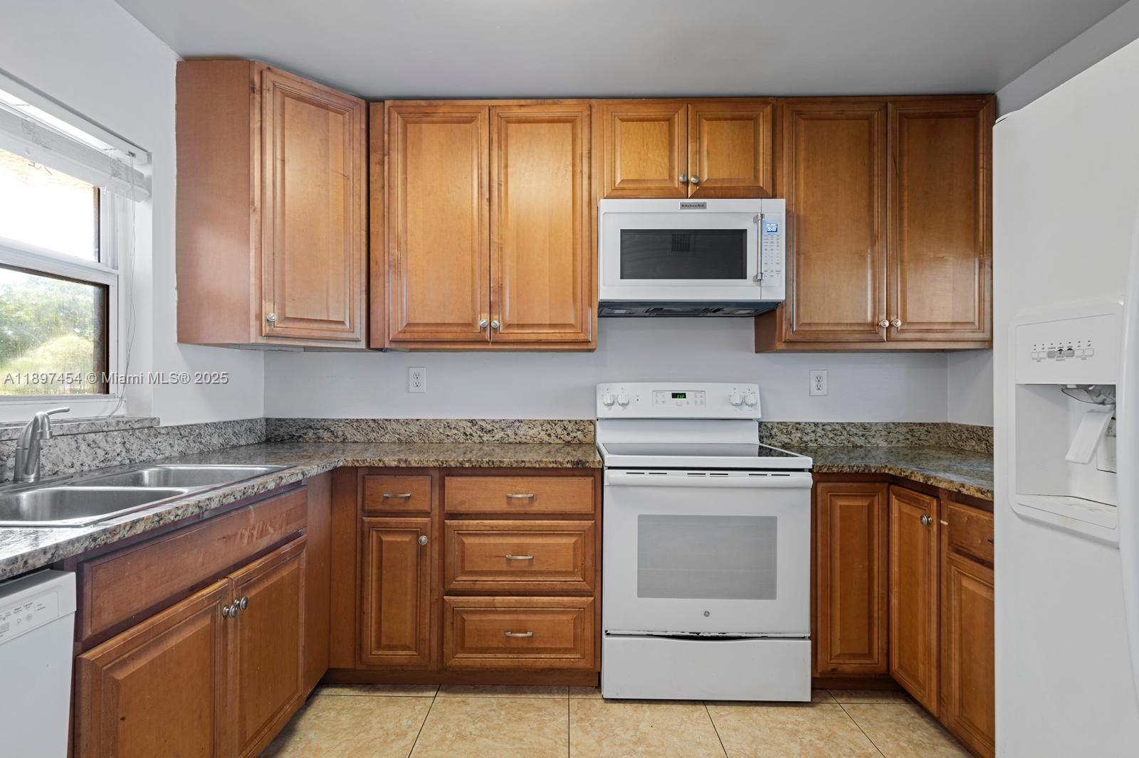 9451 Evergreen Place, Unit 303 Davie, FL 33324 - Photo 14 of 23 a kitchen with granite countertop cabinets stainless steel appliances and a sink