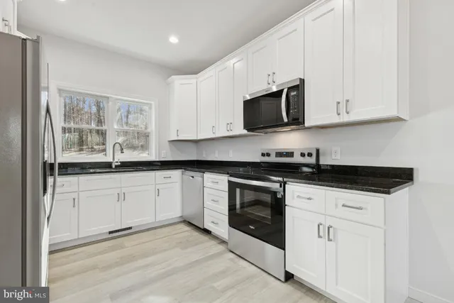 a kitchen with granite countertop white cabinets sink and stainless steel appliances