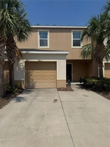 a view of a house with a yard and palm trees