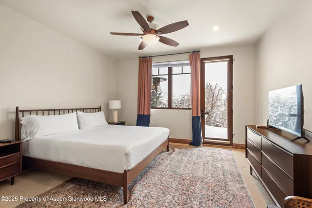 a bedroom with a large bed and a flat tv screen on dresser